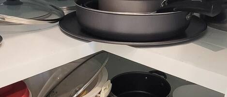 A kitchen with a stove, pots, pans, and a coffee maker.