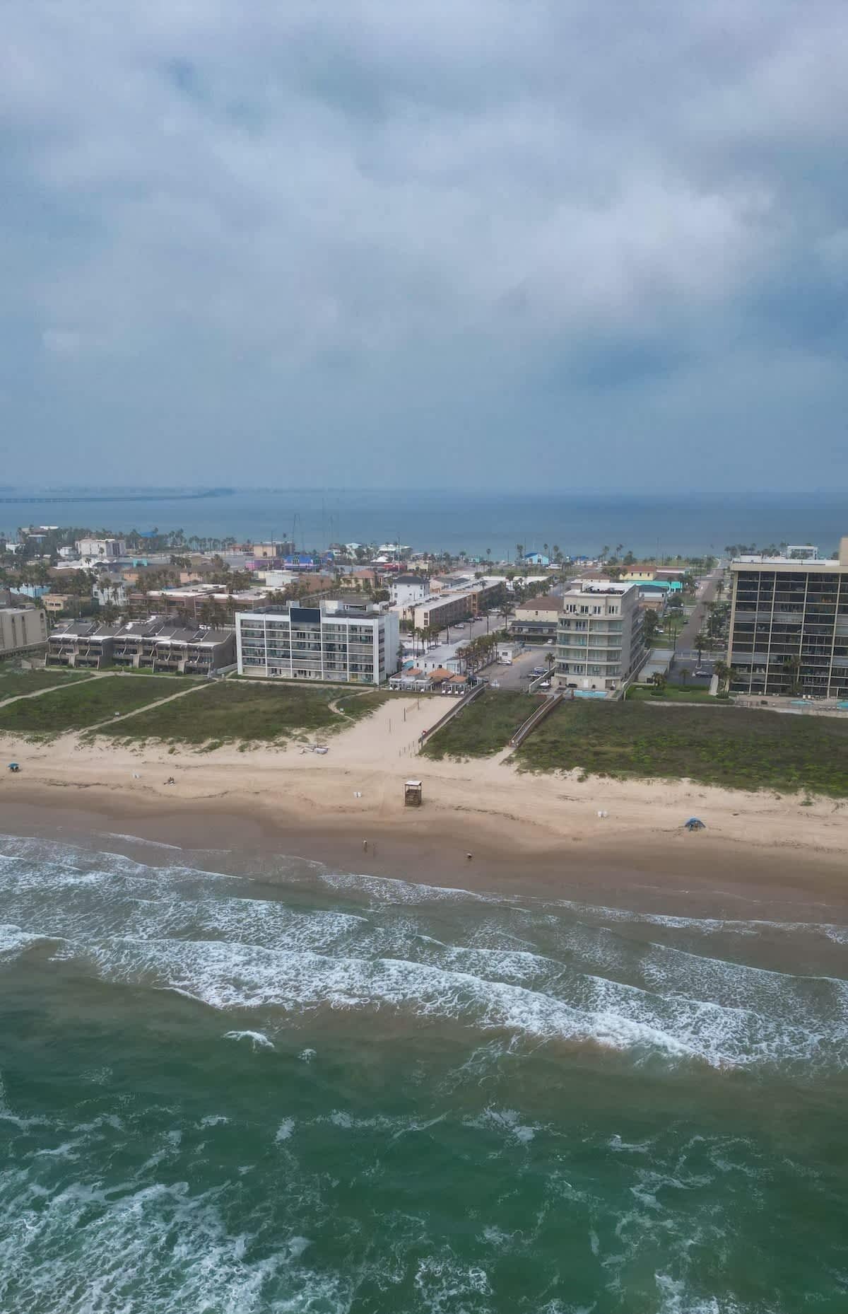 An aerial view of a coastal area with buildings, a beach, and the ocean.