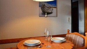 A dining table with plates, wine glasses, and cutlery, a lamp, and a painting of a boat on the wall. - 3 in Haus Pax Modern Retreat (Nebel)