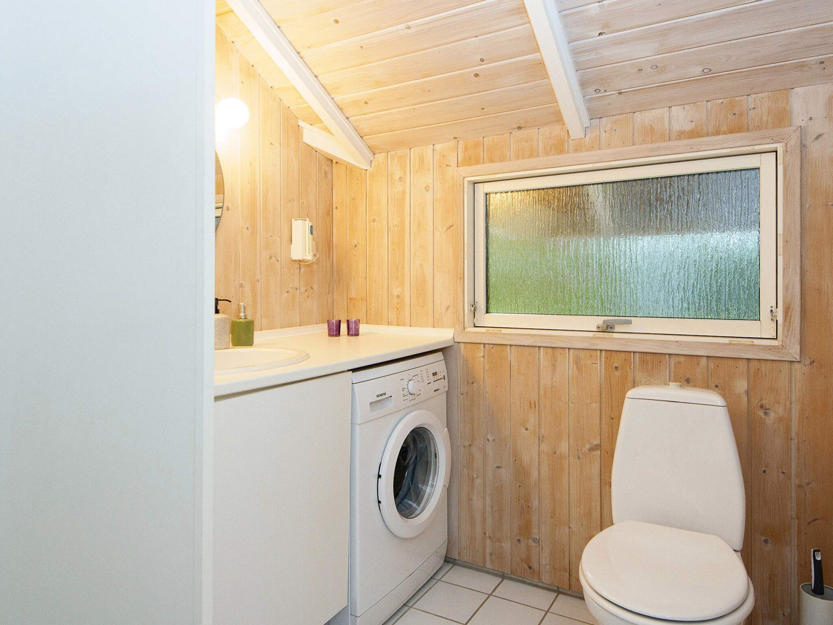 Un baño pequeño con lavadora, inodoro y ventana con vistas.