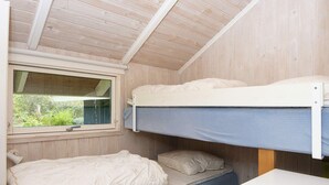 Ein Schlafzimmer mit Etagenbetten, einem Fenster, einem Schreibtisch und einem Bett mit Kissen.