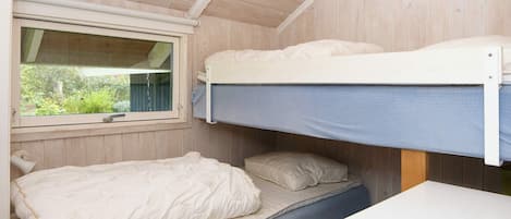 A bunk bed room with a window, a desk, and a bed with pillows.