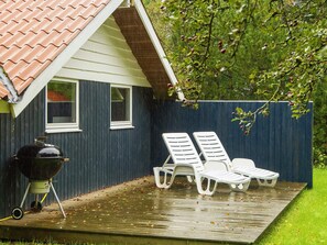 A house with a covered patio, a barbecue grill, and two white lounge chairs. - 6 Person Holiday Home in Farvang (Farvang)