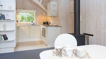 Une cuisine moderne avec des meubles blancs, une cuisinière noire et une fenêtre donnant sur un paysage verdoyant.
