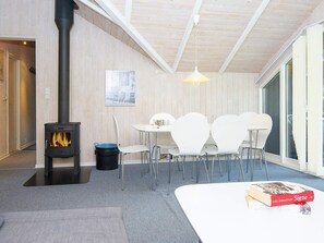 A cozy room with a wood-burning stove, a dining table with chairs, and a book on the table. - 6 Person Holiday Home in Farvang (Farvang)