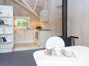 A modern kitchen with wooden walls, a black stove, and a window overlooking greenery. - 6 Person Holiday Home in Farvang (Farvang)