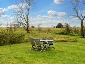 A grassy outdoor area with a table and chairs, surrounded by trees and a view of the sea. - 6 Person Holiday Home in Grenaa (Grenaa)