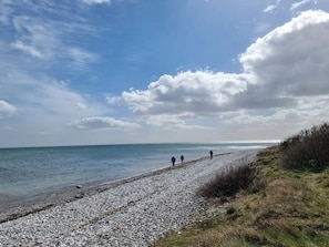 A pebbled beach path leading to the sea with a clear sky and a few clouds. - 6 Person Holiday Home in Grenaa (Grenaa)
