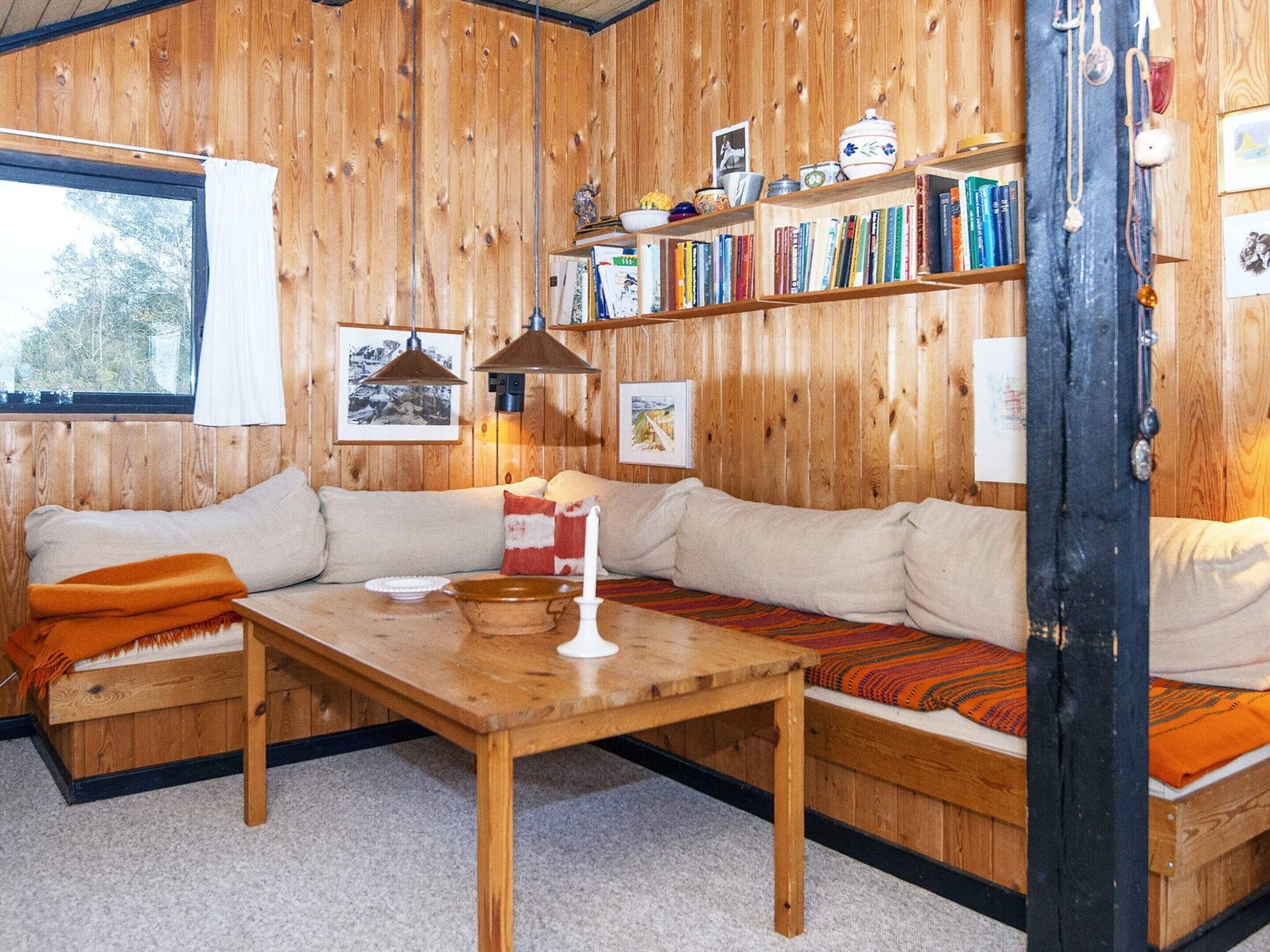 Una habitación acogedora con pared de madera, un sofá, una mesa y una estantería llena de libros.