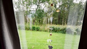 Ein Fenster mit Blick auf einen grünen Rasen und Bäume.