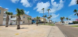 A residential street with palm trees, beige houses, and a clear blue sky. - Los Cabos I #5 2 Bedroom Condo by RedAwning (South Padre Island)
