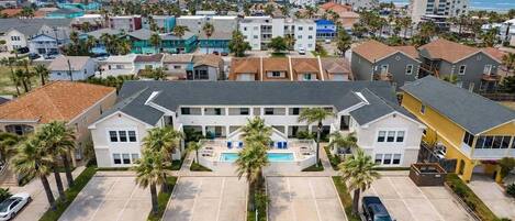 A multi-story building with a central courtyard, parking spaces, and a view of the surrounding neighborhood.