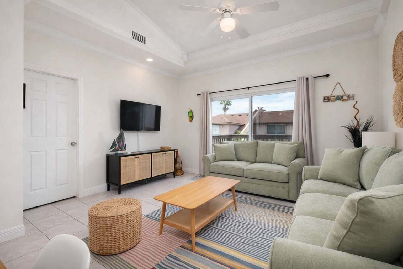 A living room with a sofa, a coffee table, a TV, and a window with a view.