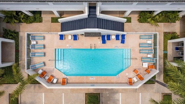 An aerial view of a swimming pool with lounge chairs and a covered seating area.