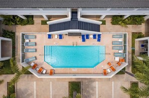 Vista aérea de una piscina con sillas de descanso y una zona de estar techada.