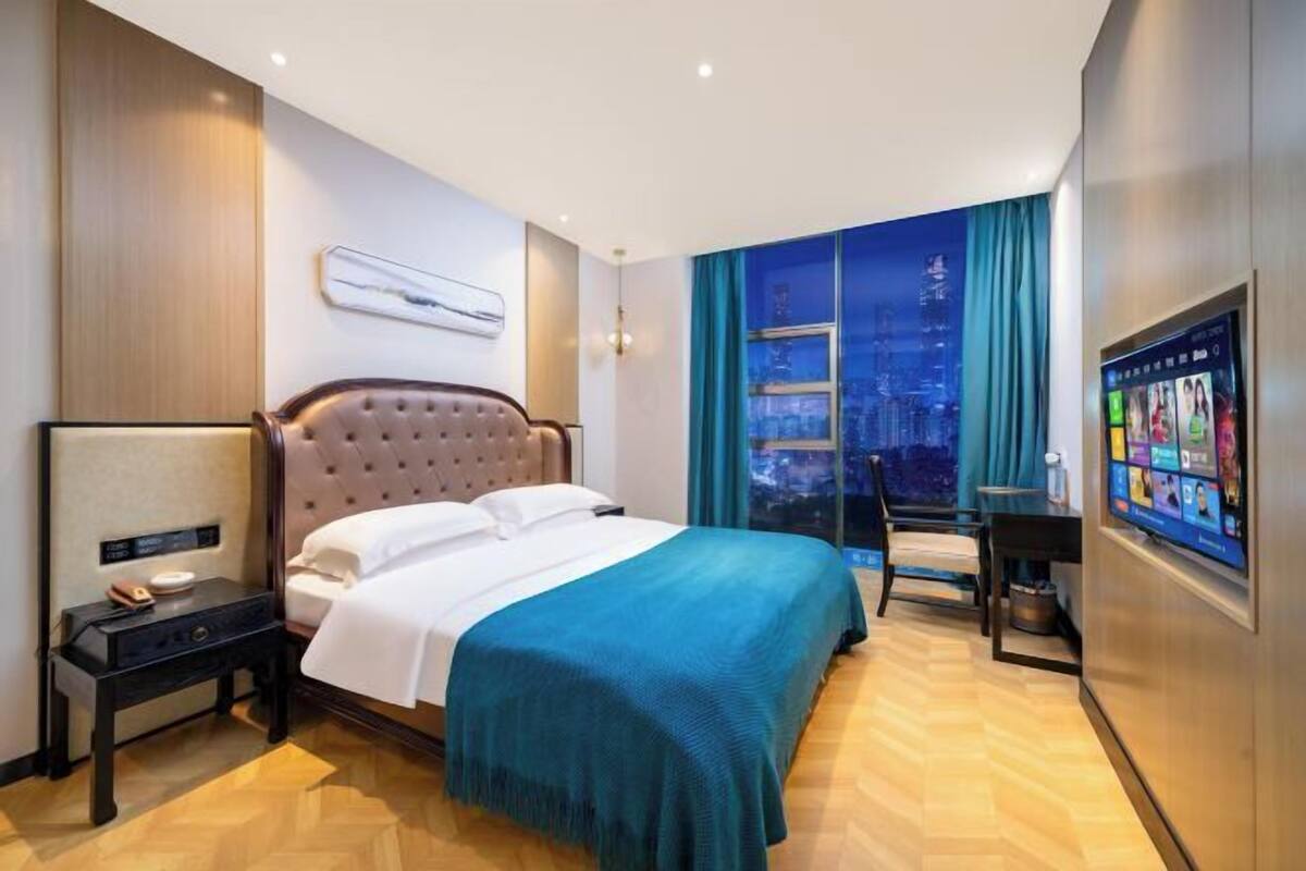Une chambre d’hôtel avec un grand lit, un bureau, une chaise, une télévision et une vue sur la ville.