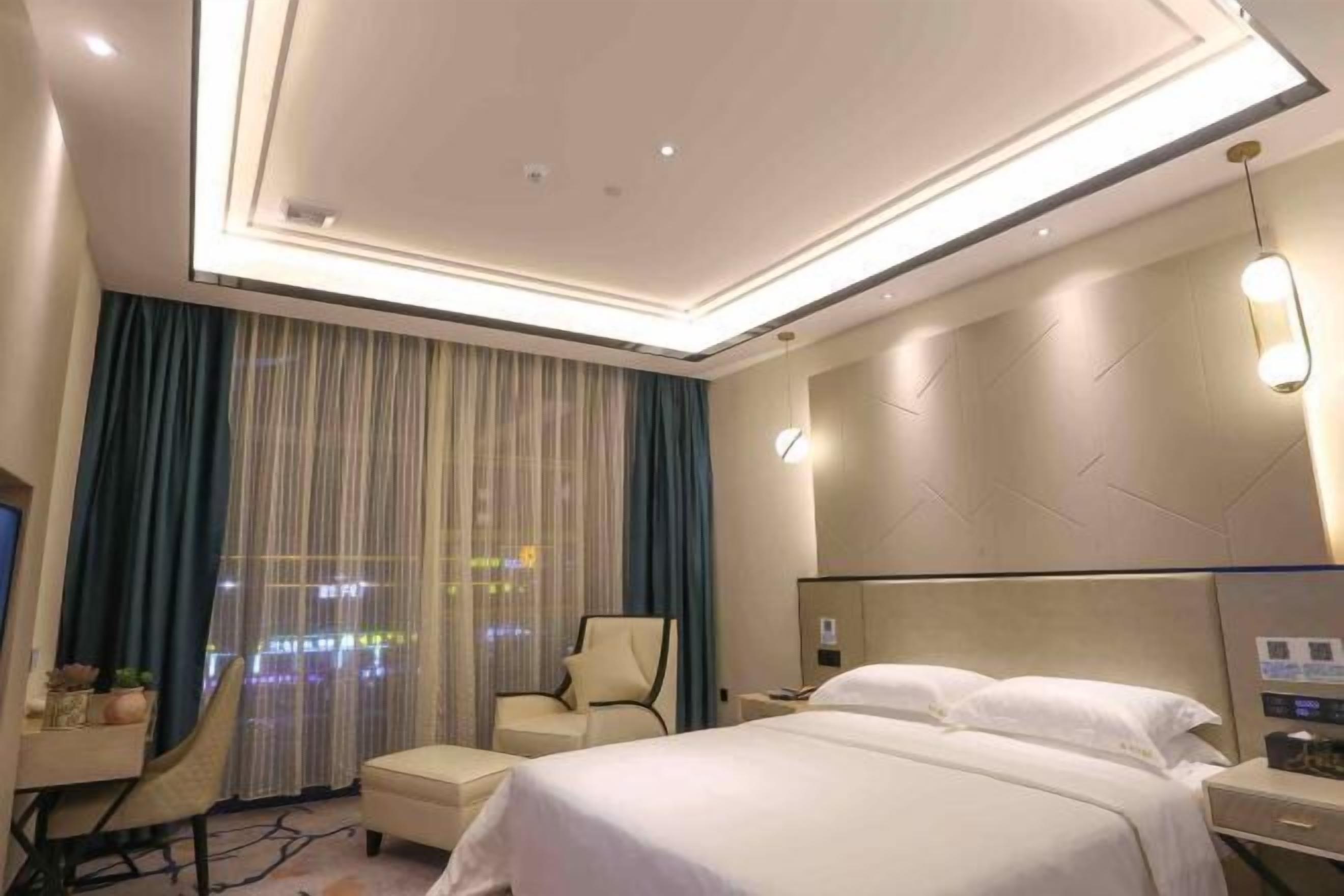 Ein Hotelzimmer mit einem großen Bett, einem Schreibtisch mit Stuhl, einem Nachttisch und einem an der Wand montierten Fernseher.
