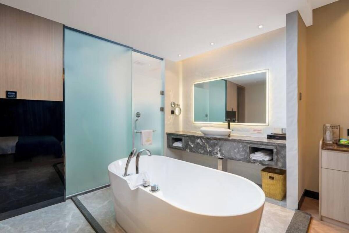 Une salle de bain moderne avec une baignoire sur pieds, un grand miroir et un meuble-lavabo.