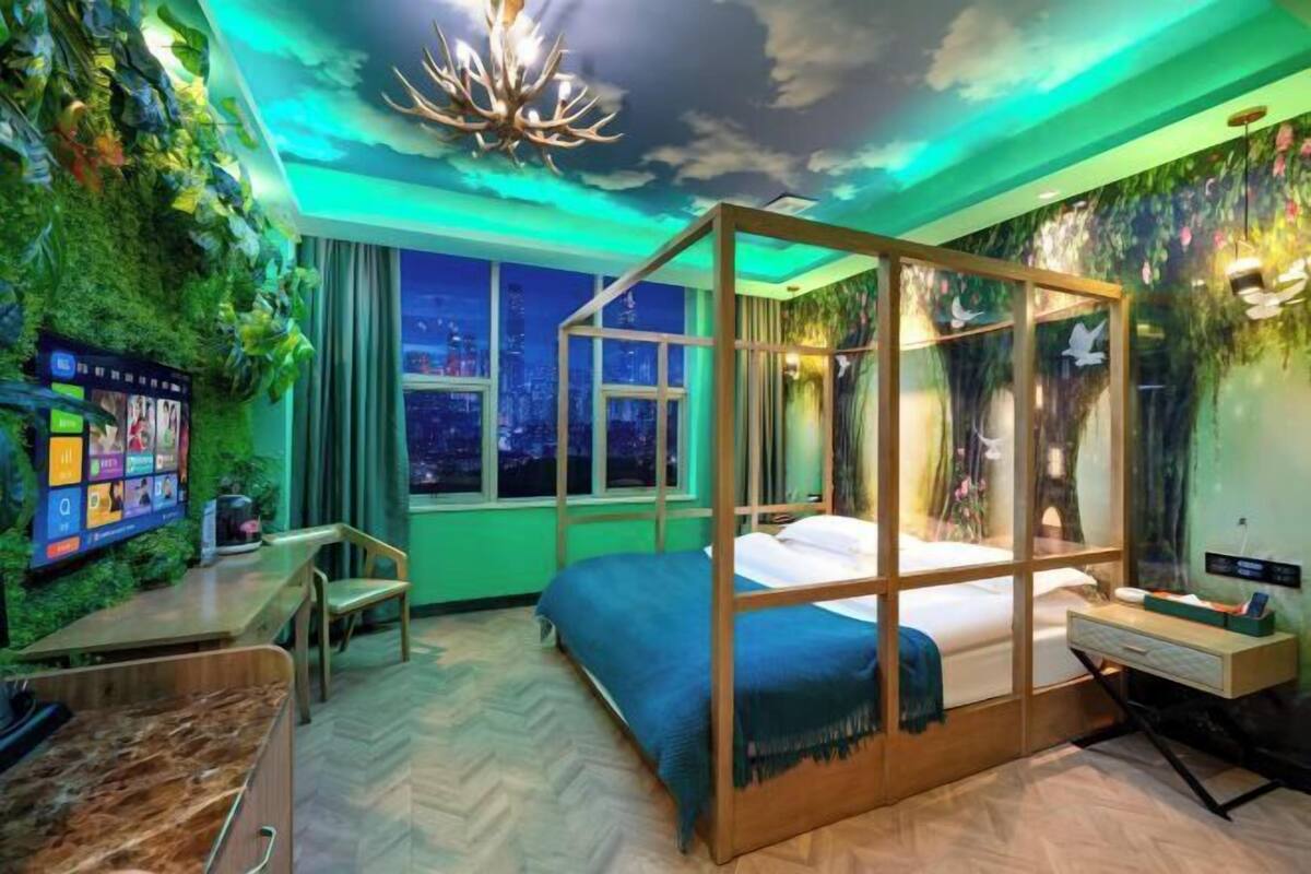 Une chambre avec un lit, un bureau, une télévision et une vue sur la ville la nuit.