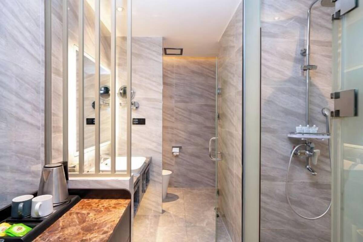 Une salle de bain moderne avec une douche à l’italienne en verre, un plan de toilette en marbre et des toilettes apparentes.