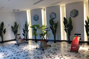 A fitness area with exercise equipment and large potted plants.