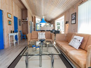 A modern interior with a glass coffee table, leather sofas, and wooden walls.