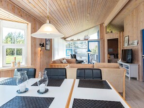 A cozy cabin interior with a dining area, seating, and a television.