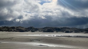 Une plage avec des dunes de sable et un ciel nuageux.