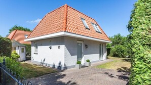A single-story house with a red-tiled roof, a white exterior, and a paved driveway. - Holiday Home Dune Nest (Noordwijk)