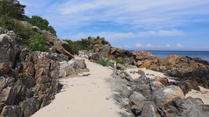 Un camino costero rocoso con una vista despejada al mar y un cielo parcialmente nublado.
