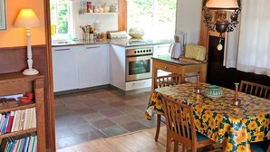 Una cocina acogedora con armarios blancos, una estufa y un comedor con una mesa cubierta con un mantel de girasoles.