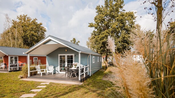 A two-story house with a covered patio, a lawn, and a pathway leading to the entrance. - Chalet With Covered Terrace in the Leukermeer (Well)