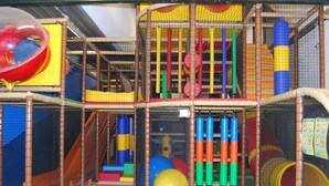 Un área de juegos interior con diversas estructuras, como toboganes, túneles y elementos para escalar.