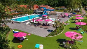 Zona de piscina con varias piscinas, tumbonas y sombrillas.