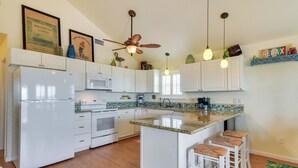 A modern kitchen with white cabinets, a central island with bar stools, a ceiling fan, and pendant lighting. - Walk to Shore: Surfside Beach Home w/ Bay Views (Freeport)