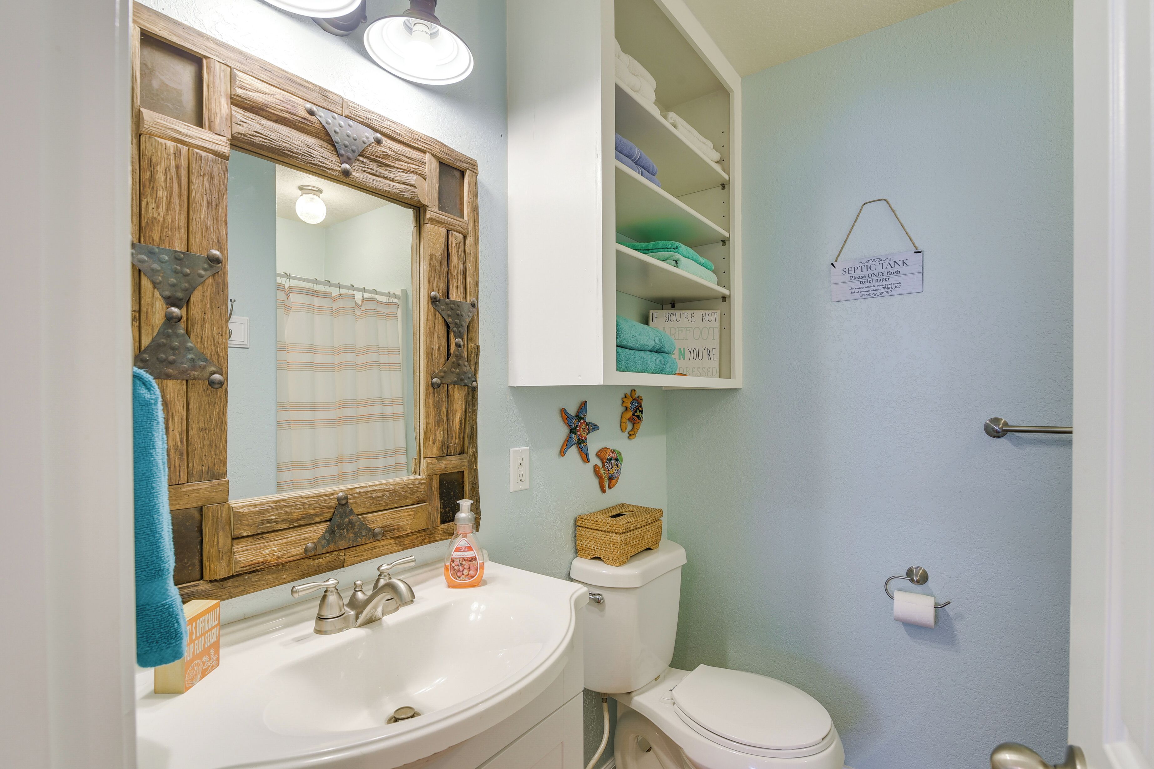 A bathroom with a wooden vanity, a toilet, and a shelf with towels.