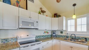A kitchen with white cabinets, a microwave, a stove, and a sink. - Walk to Shore: Surfside Beach Home w/ Bay Views (Freeport)