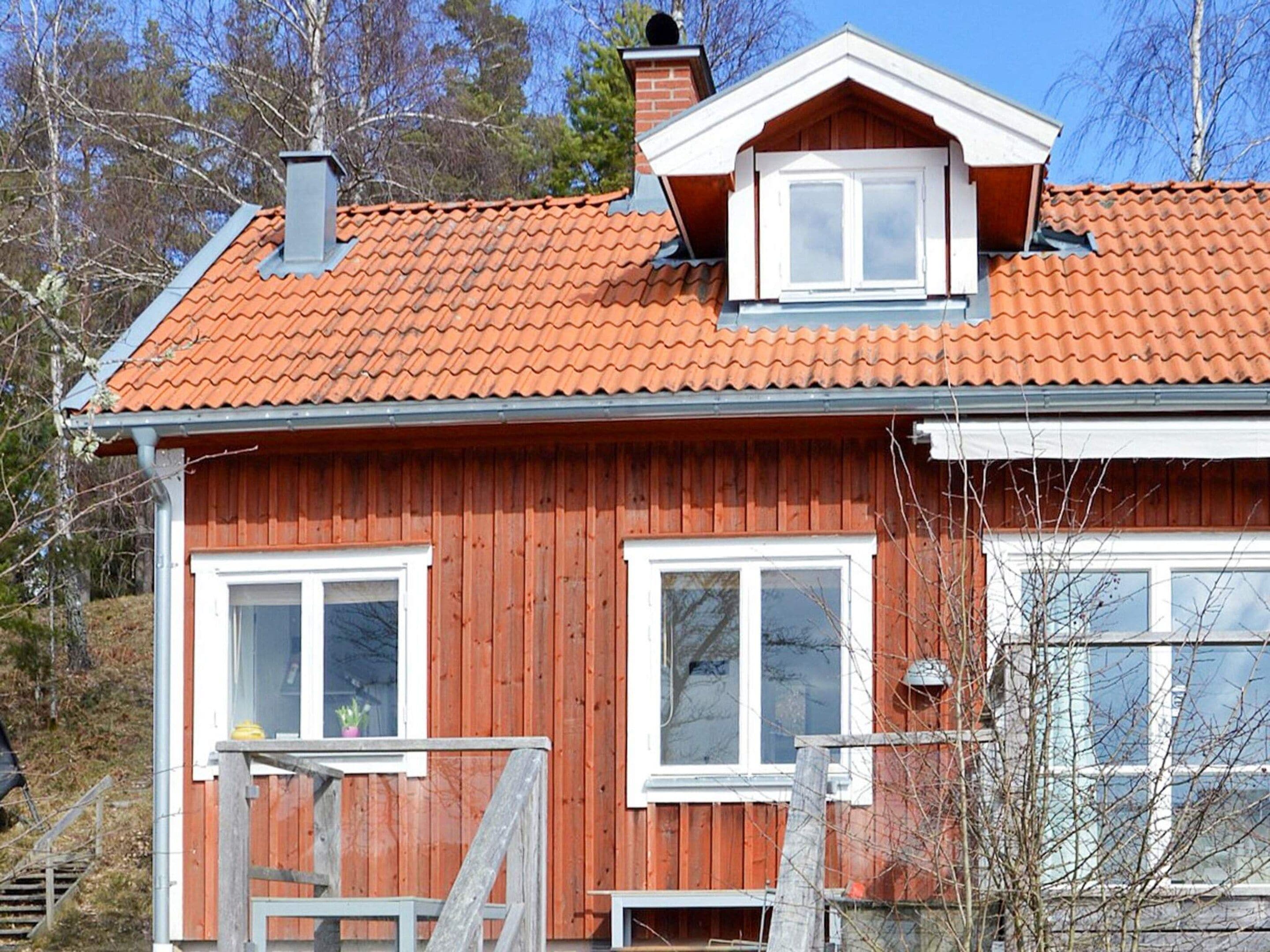 A two-story house with a red-tiled roof, white-framed windows, and a visible chimney.