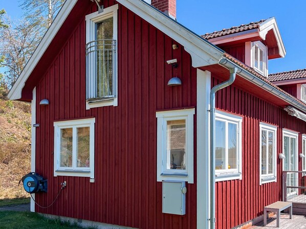Un bâtiment rouge avec de nombreuses fenêtres, une cheminée et un petit espace extérieur aménagé pour s’asseoir.