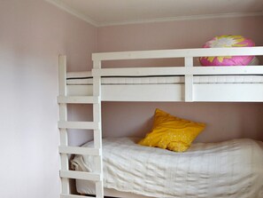 Un lit superposé avec une échelle, un lit simple en dessous et un oreiller sur le lit du bas.