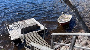 A wooden dock extending into a lake with a small boat tied to a tree. - 5 Star Holiday Home in Hjaltevad (Hjältevad)