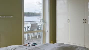 A bedroom with a bed, a wardrobe, and a door leading to an outdoor area with a table and chairs.