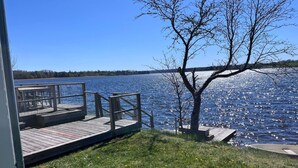 A wooden dock extending into a calm lake, surrounded by grassy areas and a clear blue sky. - 5 Star Holiday Home in Hjaltevad (Hjältevad)