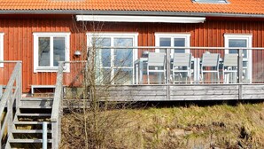 A red wooden house with a balcony, white windows, and a wooden staircase leading to the entrance. - 5 Star Holiday Home in Hjaltevad (Hjältevad)