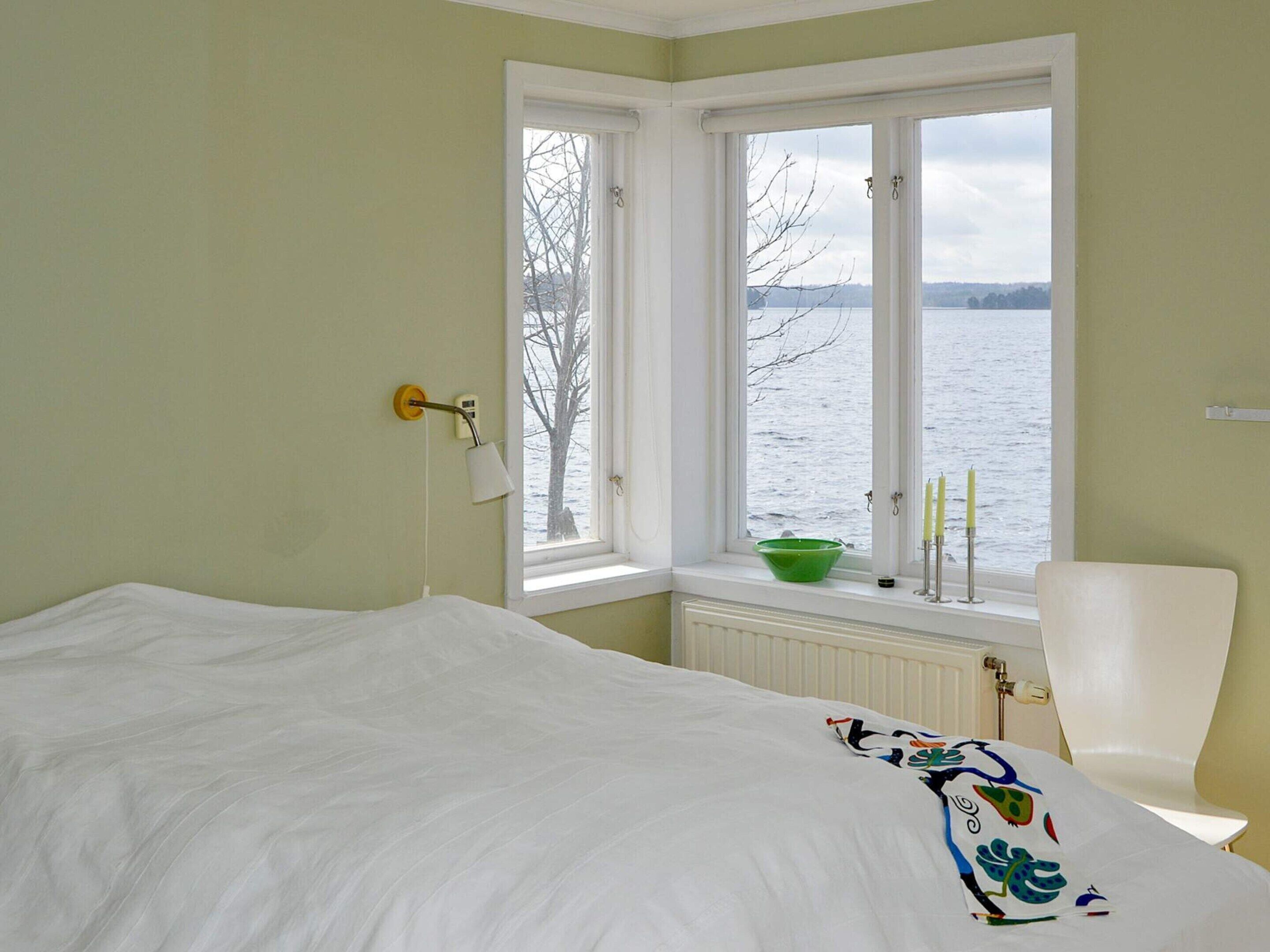 Un dormitorio con una cama, una ventana con vistas al agua y una silla.