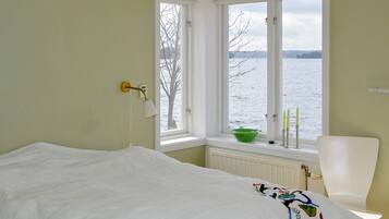 Un dormitorio con una cama, una ventana con vistas al agua y una silla.
