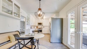 A modern kitchen with white cabinets, a stainless steel refrigerator, and a dining area with a round table and chairs. - Sonoma County Vacation Rental w/ Vineyard Views! (Sebastopol)