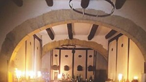Een ruime hal met gewelfd plafond en stenen bogen, met tafels en stoelen voor dineren of gezellig samenzijn.