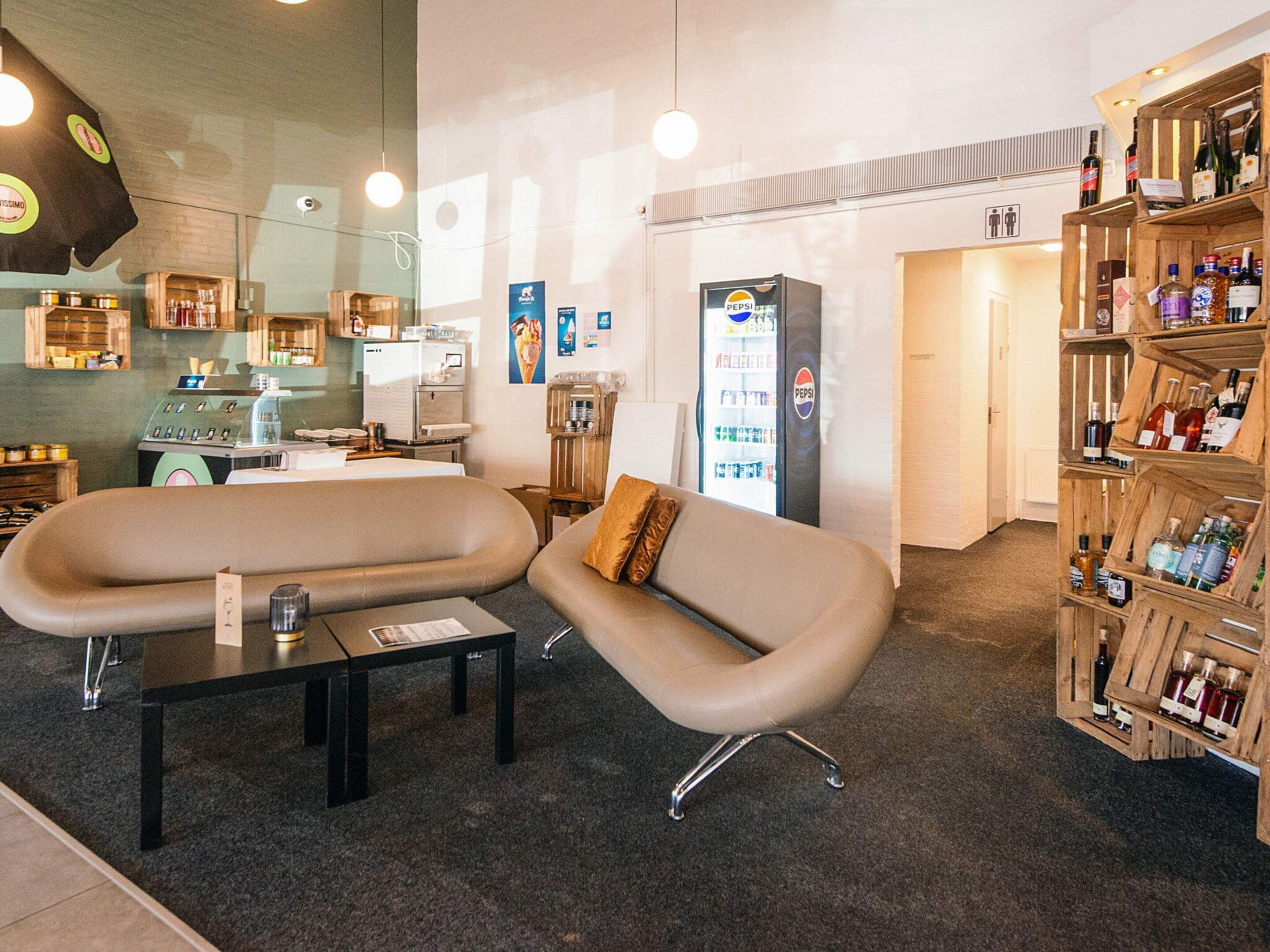 Un espace détente moderne comprenant un canapé, une machine à café, un réfrigérateur et un meuble à bouteilles.