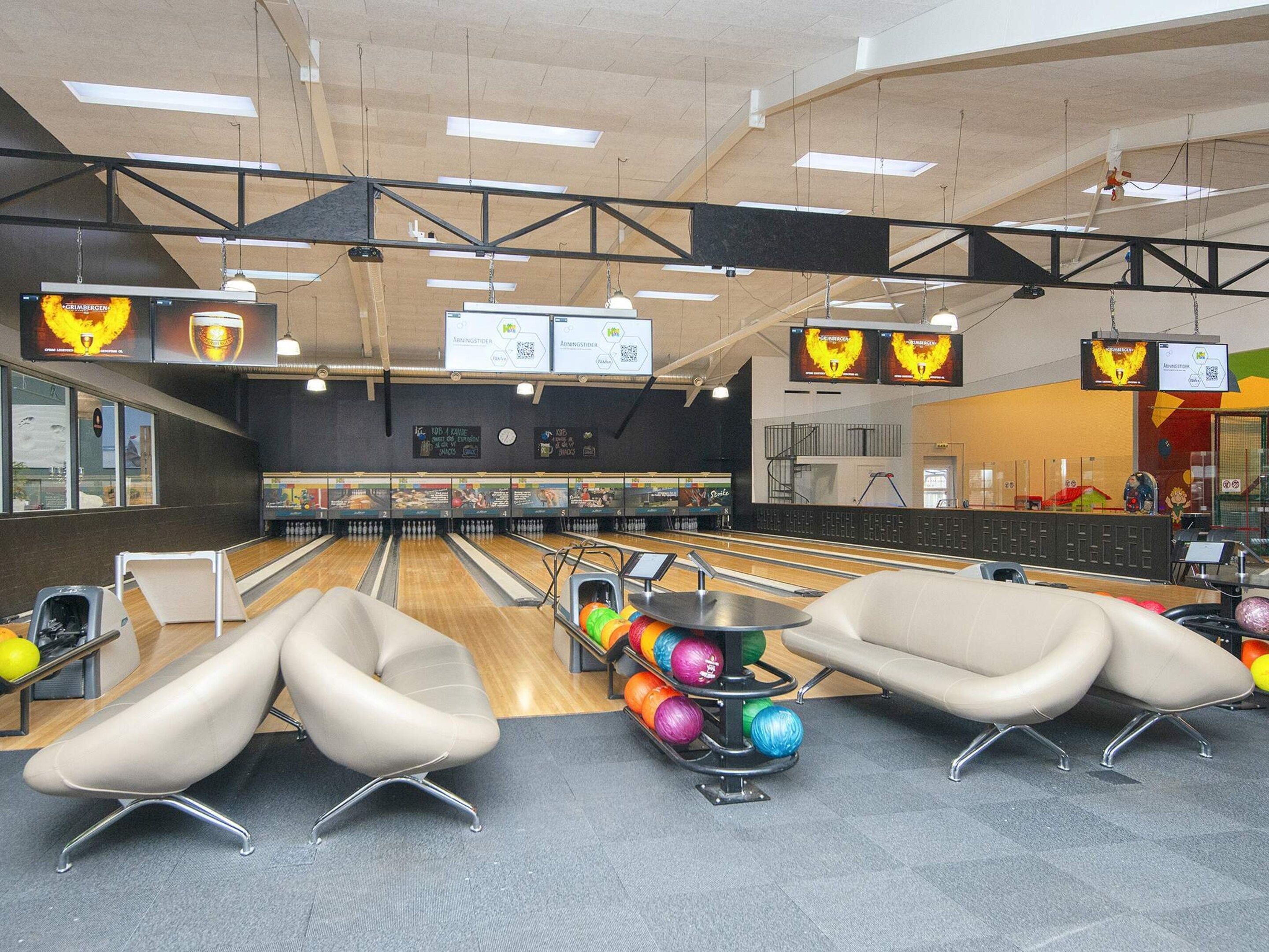 A bowling alley with multiple lanes, a snack bar, and seating areas.